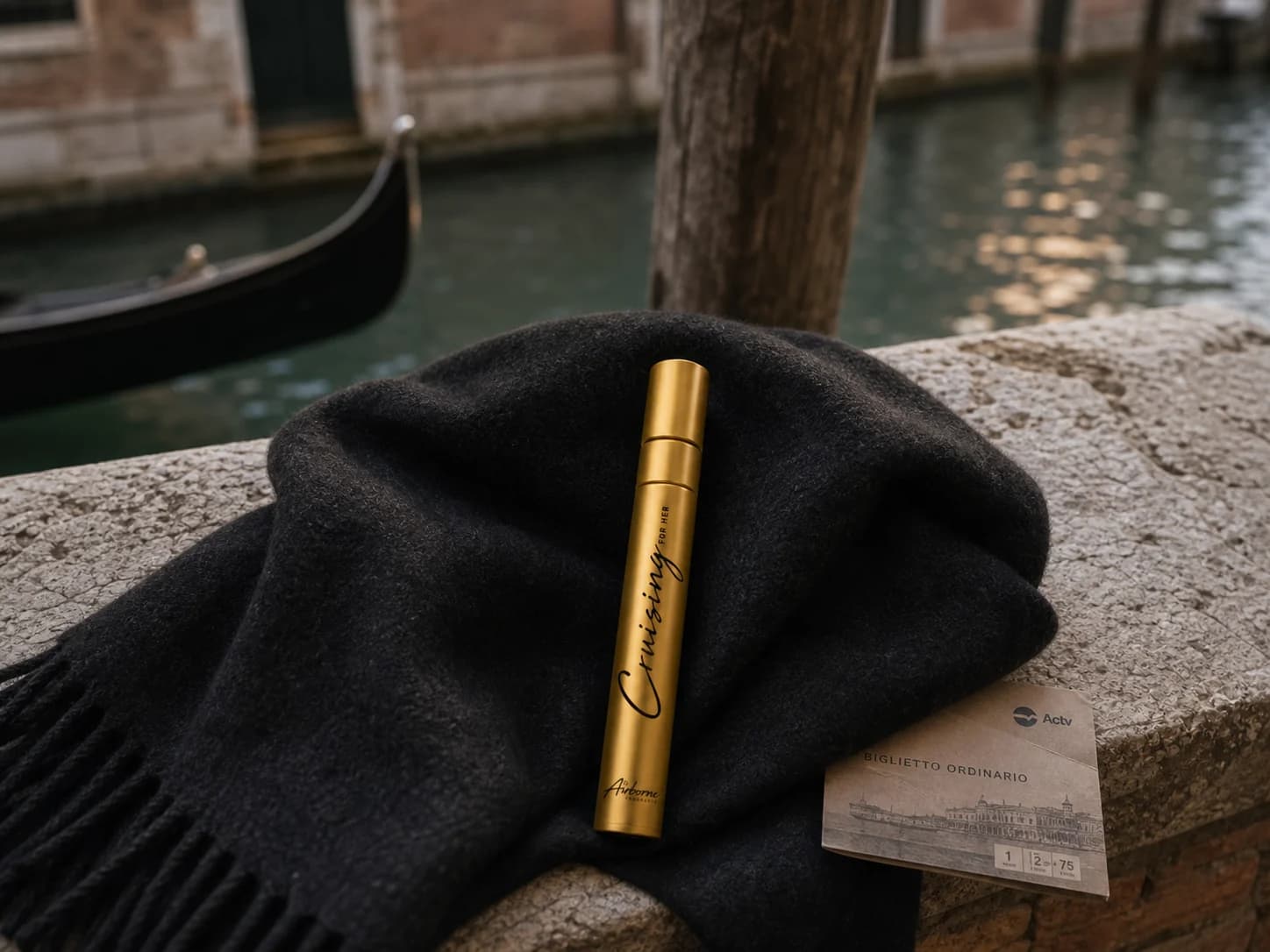 Cruising travel atomizer resting on a black scarf beside a Venice canal